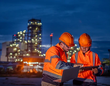 Engineers with helmets laptop onsite.