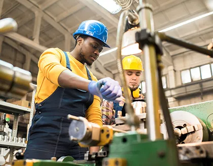 two men in hardhats working in factory.