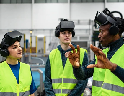 Team of multiracial engineers having a simulation experience with futuristic virtual reality glasses inside robotic factory.