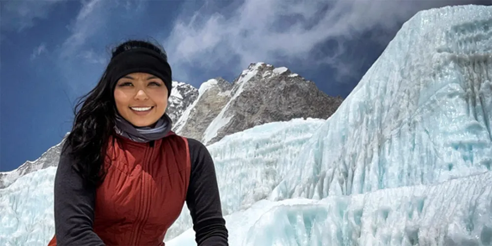 woman with long dark hair smiling in front of mountain glaciers